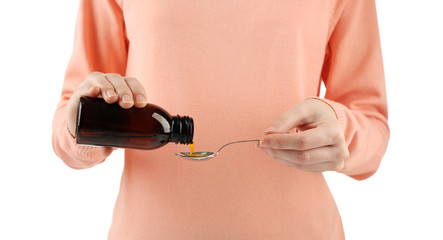 Woman pouring cough medicine syrup into spoon on white background