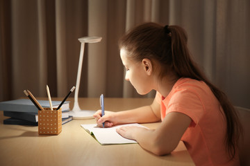 Incorrect posture concept. Schoolgirl sitting at table in room