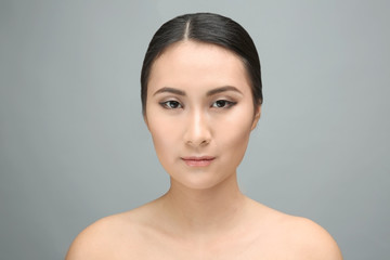 Portrait of beautiful Asian woman on gray background