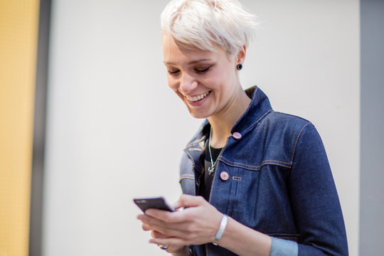 Young adult walking down street and checking smartphone