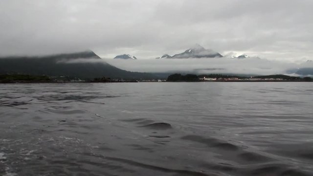 Unique landscape of mountains in fog on background of watery surface in Alaska. Beautiful rest and tourism in a cool climate. Unique picture of nature in America.