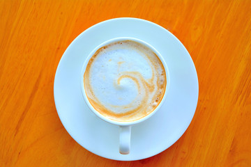 A cup of coffee  in a white cup on wooden background