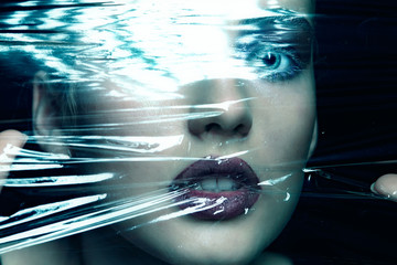 Halloween beauty portrait of young woman looking through a polyethylene film