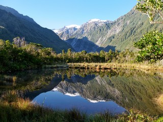 Naklejka na ściany i meble Small pond with reflection of mountain glacier