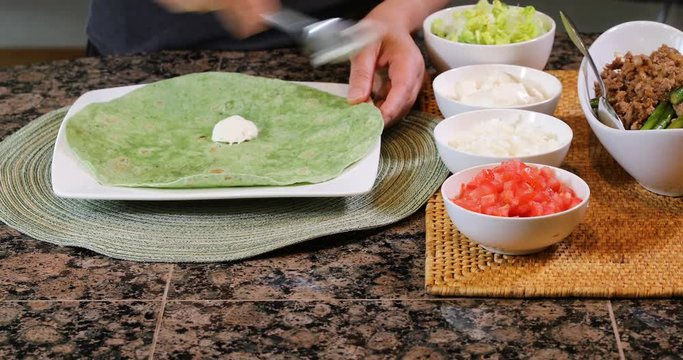 Female hands making taco with fresh ingredients 