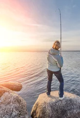 Foto op Plexiglas Vissen Girl hooking a fish on the shore of the lake
