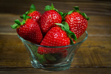 Organic  red strawberries in a bowl on a wooden background