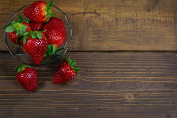 Organic  red strawberries in a bowl on a wooden background