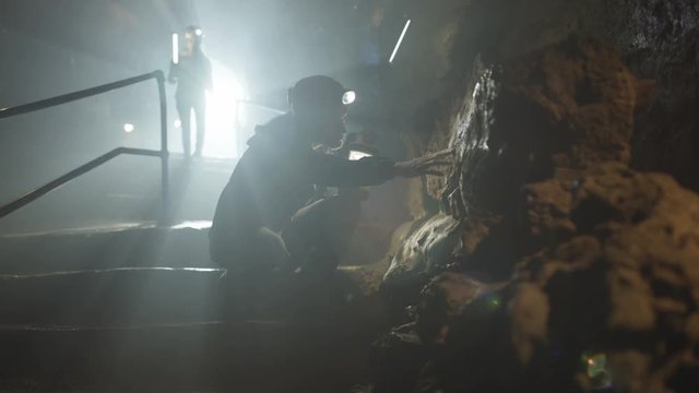  Team of potholers with hard hats and lamps exploring underground cave system
