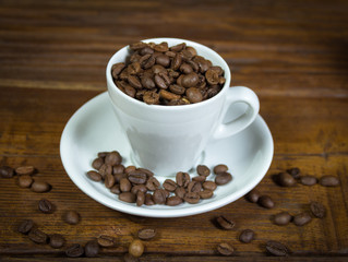A full cup of coffee with coffee beans on a wooden background