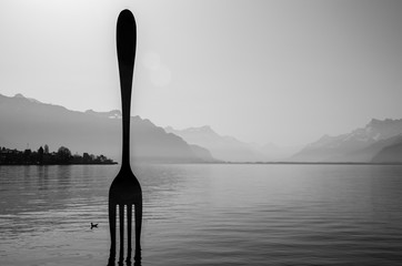 A scene of Geneva lake in black-white tone with giant fork in the middle in Vevey town