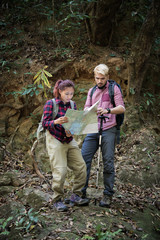 Young tourist couple traveling on holidays in forest looking at map in search of attractions. Travel concept.
