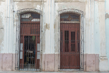 CIENFUEGOS, CUBA - DECEMBER 31, 2016:  Old house facade with people inside, street view