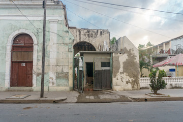 Fototapeta na wymiar CIENFUEGOS, CUBA - DECEMBER 31, 2016: Old house facade with people inside, street view