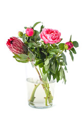 Bright bouquet of freshly cut flowers in a glass vase on a clean white background..