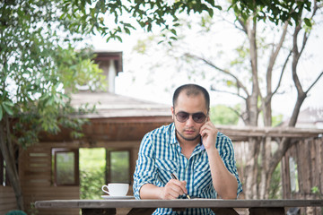 Fototapeta premium Young businessman using smartphone while working in the home garden.