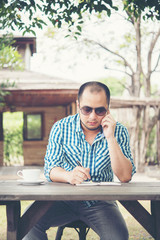 Fototapeta premium Young businessman using smartphone while working in the home garden.
