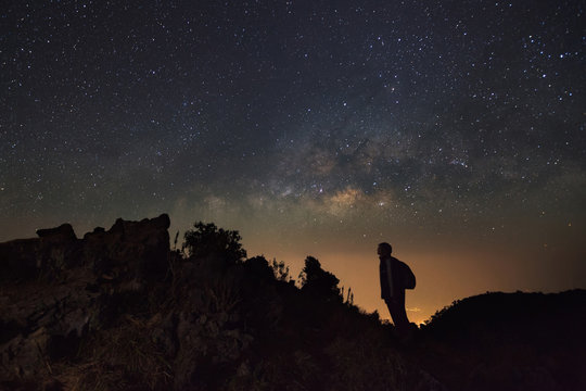 Landscape with milky way, Night sky with stars and silhouette of a standing man at Doi Luang Chiang Dao with Thai Language top point signs. Long exposure photograph.With grain