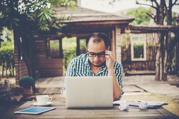 Young businessman with glasses working at workplace, feeling stressed, looking at laptop.