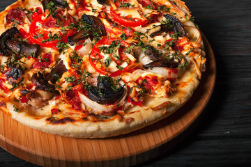 Fresh tasty pizza on black background on rustic wooden table with ingredients. Italian food.