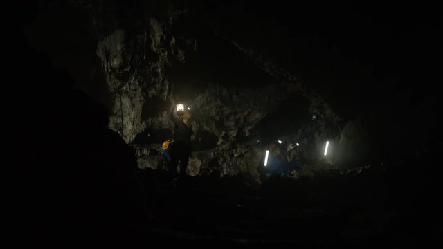  Geologists exploring underground cave, discussing rock formation