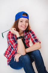 Closeup portrait. Skateboarder having fun in red plaid shirt, jeans, blue cap. Hipster girl style posing, smiling, do fake mustache on a  isolated white background. Swag style. Look into the camera.