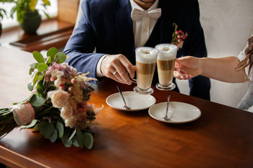 Bride and groom clapping cappuccino, wedding couple clinking glasses with coffee with milk at wedding day