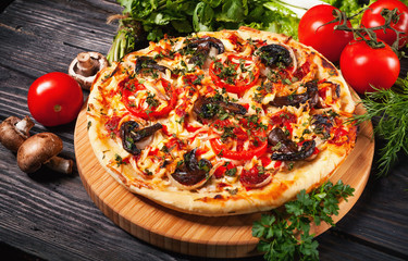 Fresh tasty pizza on black background on rustic wooden table with ingredients. Italian food.