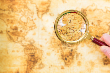 Old map and magnifying glass in a hand