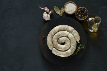 Raw homemade sausage on a black background with spices and herbs. copy space