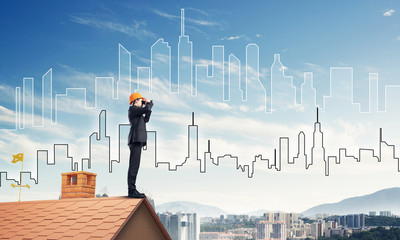 Engineer man standing on roof and looking in binoculars. Mixed m