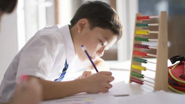  Young school children in class with little boy using an abacus