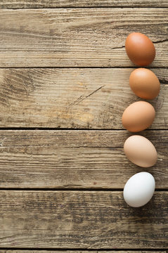 Eggs of different colors on wooden background