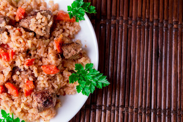 Pilaf on the white plate on a wooden table. Top view. Copy space.