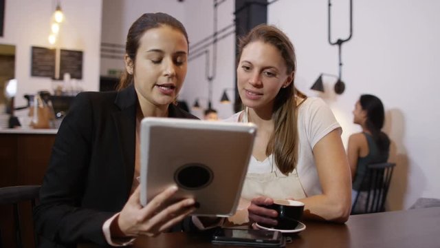  Sales rep with computer tablet negotiating a deal with cafe owner