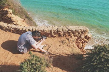 Young photographer making photos of a seascape with his camera