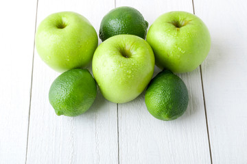Green fruits on white wooden background. Apple, lime. Detox. Healthy food. Close up.