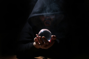 man in a black hood with cristal ball 