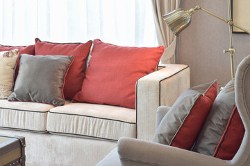 Classic industrial look living room with beige sofa and red and deep brown linen pillows with brass reading lamp