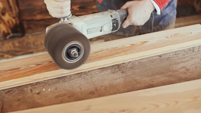 The working joiner processes boards. Wire brush during machining wood. Brushing wood work.