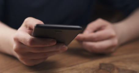 young female teen hand using smatphone sitting at the table closeup, 4k photo