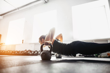 Young strong girl doing push-ups on kettlebells. focus on kettlebells
