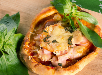 Mini pizza with ham,sausage,tomatoes,cheese and Basil
