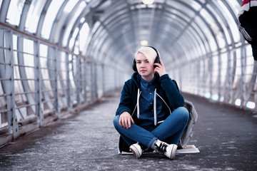 Young student listening to music in big headphones in the subway