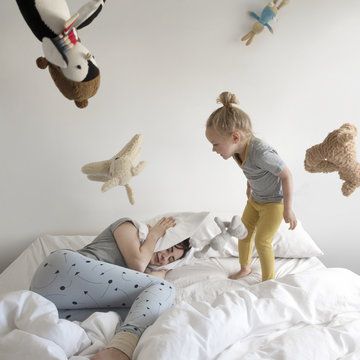 Little girl waking mother up early throwing toys