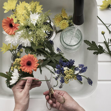 Chopping and arranging flowers in kitchen sink
