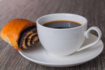 Loaf with poppy seeds and a Cup of coffee on the table. Selective focus.
