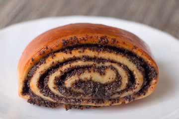 Roll with poppy seeds on a plate. Selective focus.