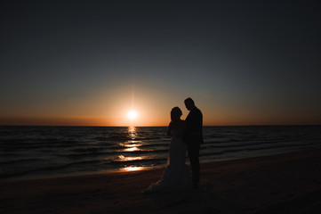 Fototapeta na wymiar Just Married. Beautiful young couple on the beach at sunset