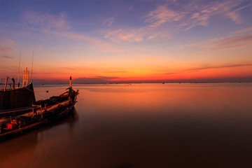 Fototapeta na wymiar Sunset over sea shore and silhouette shell farm with fishing boat